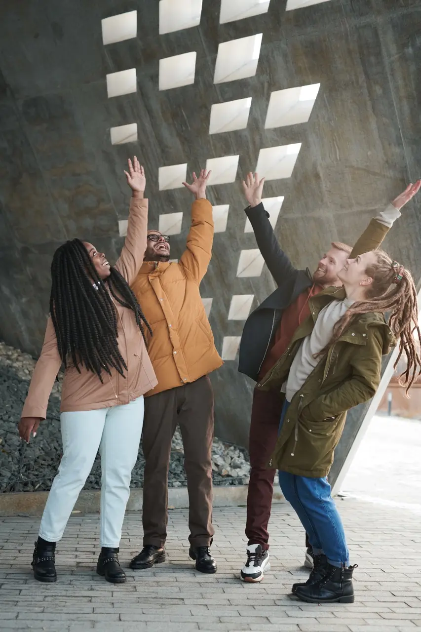Multiethnic group of friends exchange high-fives outside an industrial structure